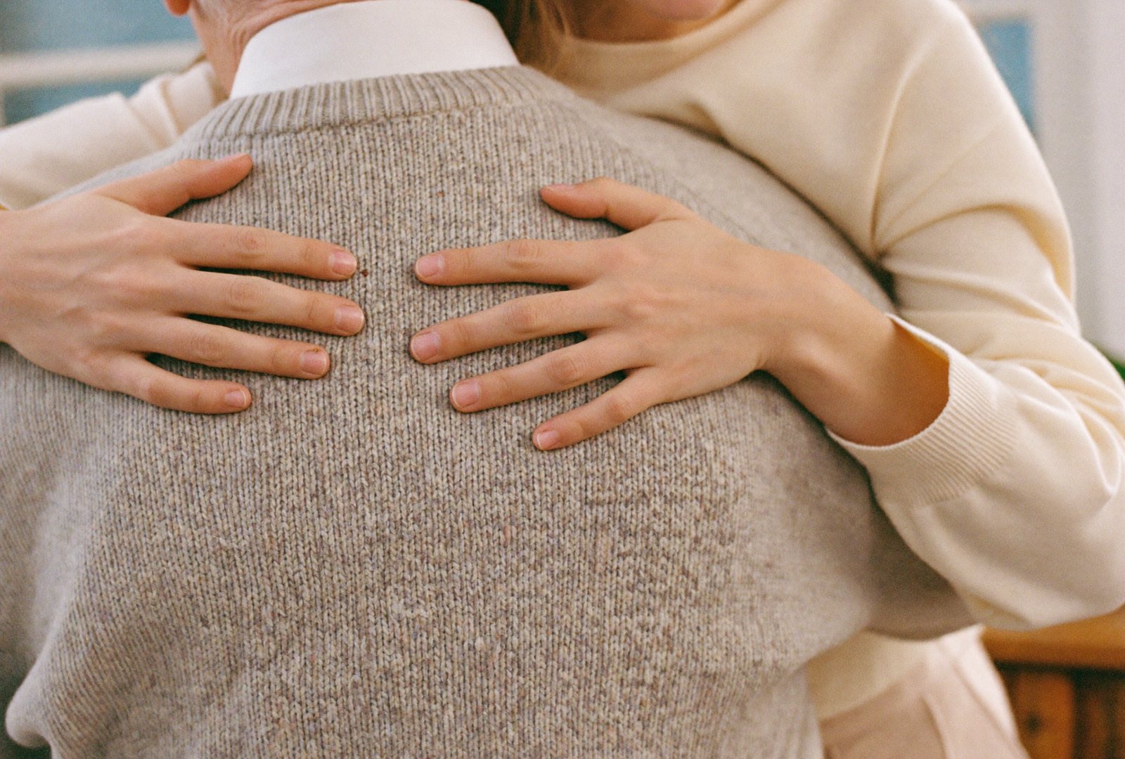 Duas mãos a abraçar uma pessoa idosa